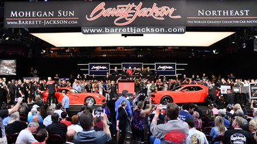 A Dodge Viper and a Dodge Challenger sit nose-to-nose on an auction stage