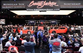 A Dodge Viper and a Dodge Challenger sit nose-to-nose on an auction stage