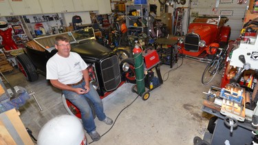 Mike Siewert sits on the front wheel of his dad’s 1928 Model A in his action-packed garage.