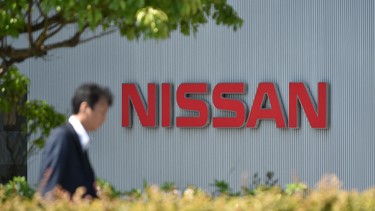 This file photo taken on May 11, 2017 shows a man walking in front of the logo of Japan's Nissan Motor Corporation at its global headquarters in Yokohama, Kanagawa prefecture.