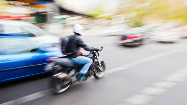 A motorcycle driving by cars on a city street.