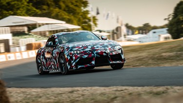 camoflaged sports car zipping around hay bales on paved track