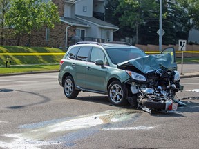 A motorcycle lies underneath a Subaru SUV in a fatal crash along Old Coach Banff Road in Calgary on Wednesday, Aug. 12, 2015.