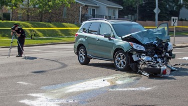 A motorcycle lies underneath a Subaru SUV in a fatal crash along Old Coach Banff Road in Calgary on Wednesday, Aug. 12, 2015.