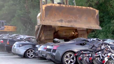 A row of Porsches, Lamborghinis and Mustangs are crushed under the tracks of a bulldozer in the Philippines July 30, 2018. The country's policy is to publicly destroy vehicles illegally imported without tax paid.