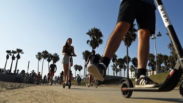 People ride Bird shared dockless electric scooters along Venice Beach on August 13, 2018 in Los Angeles, California.