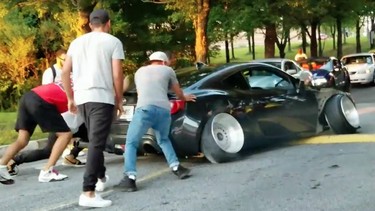 A modified Scion gets stuck on a speed bump.