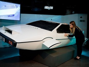 A woman poses with "Wet Nellie" from the James Bond film "The Spy Who Loved Me" at the press preview for the exhibition "Bond in Motion" at the London Film Museum in central London on March 18, 2014.