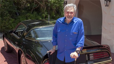 The late Burt Reynolds standing beside his personal Pontiac "Bandit" Trans Am.