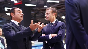French President Emmanuel Macron (R) listens to CEO of French carmaker Renault Carlos Ghosn during an official visit at the Paris auto show in Paris, on October 3, 2018.
