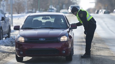 Const. Sean Strang of the CN Police force speaks to a driver in Regina, Saskatchewan about safe winter driving around railway tracks during a traffic awareness stop in the 500 block of Elphinstone St. in November 2017.