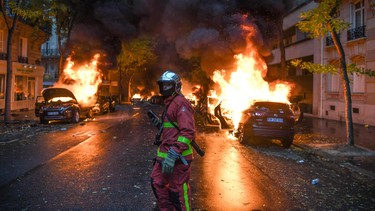 A firefighter looks on as cars are burning during a protest of Yellow vests (Gilets jaunes) against rising oil prices and living costs, on December 1, 2018 in Paris.