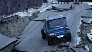A Jeep CJ-7 in Alaska crossing an earthquake-ravaged pass of highway.