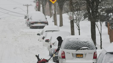 In this file photo, a man uses a snowblower to clear snow from around cars on Sunday, Jan. 20, 2019, in Albany, N.Y.