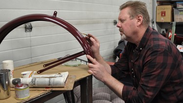 Calgary artist Tom Tracey at work with his pinstripe brush, adding a thin gold line to pieces of a 1939 Triumph Speed Twin.