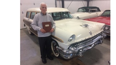 Barry Claridge holding his university thesis on new car buying trends. He sold a Mercury station wagon like this as he worked his way to a UBC Bachelor of Commerce degree.