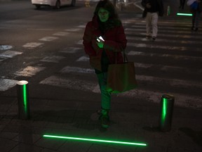 In this Wednesday, March 13, 2019 photo, an Israeli woman walks past embedded LED stoplights at a crosswalk in Tel Aviv, Israel.
