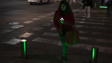 In this Wednesday, March 13, 2019 photo, an Israeli woman walks past embedded LED stoplights at a crosswalk in Tel Aviv, Israel.