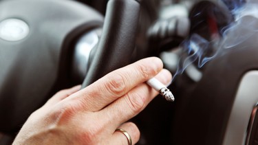 A driver smoking a cigarette in a car.