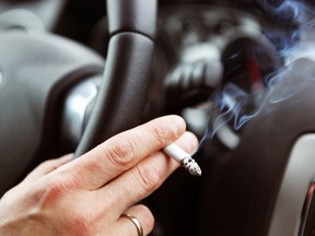 A driver smoking a cigarette in a car.