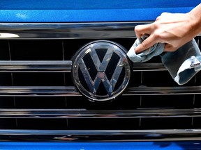 A staff member cleans the logo of a SUV VW Touareg on display ahead of the annual general meeting of German carmaker Volkswagen, in Berlin on May 3, 2018.