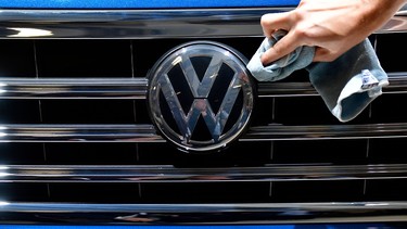 A staff member cleans the logo of a SUV VW Touareg on display ahead of the annual general meeting of German carmaker Volkswagen, in Berlin on May 3, 2018.