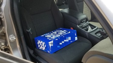 A 30-can case of beer being used as a booster seat for a child