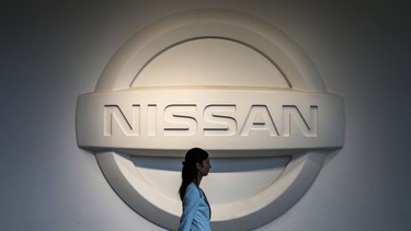 This file photo taken on May 14, 2019 shows a woman walking past a logo of Nissan Motors at the company's headquarters in Yokohama.
