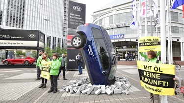Greenpeace activists protest against climate-damaging cars with an installation with a car set-up upright and banners reading "the oil age is ending" on the sidelines of the Frankfurt Motor Show IAA in Frankfurt am Main, western Germany, on September 12, 2017.
