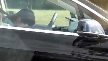 A screenshot from a video apparently of a driver asleep at the wheel of a Tesla on Autopilot.