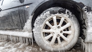 Ice buildup and icicles on a car and close-up of a frozen wheel, in Montreal, Canada.
