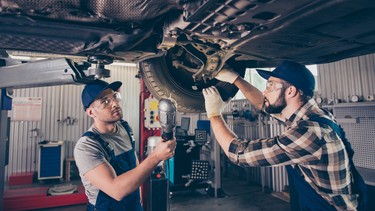 Engineering, protection, reliability, safety, oneness, colleagues, assistance. Professionals in blue overalls, protective spectacles are examining changing tires, tyres, brake pads at work shop