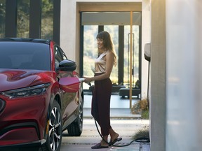A woman plugging a home electric car charger into a new Ford Mustang Mach-E EV
