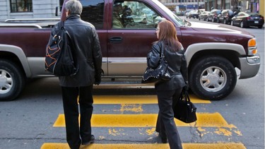 Pedestrians wait for a pick-up truck that failed to stop to let them cross the street at the crosswalk on Peel St. south of St. Catherine St. in Montreal, Monday October 31, 2011.