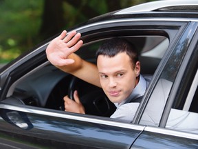 portrait of young man driving car and greeting somebody