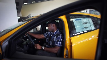 In this 2013 file photo, Anthony Gordon looks at a Ford Focus ST on the showroom floor at a Ford AutoNation car dealership in North Miami, Florida.