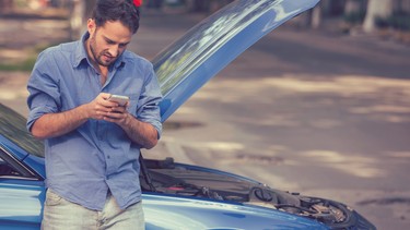 young stressed man driver having trouble with his broken car looking in frustration at failed engine