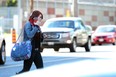 In this file photo, a woman wearing headphones crosses the street at a Toronto intersection
