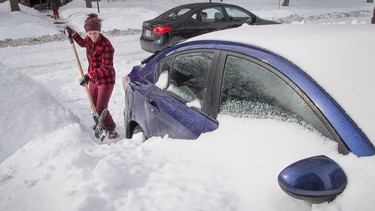 In this file photo, masters student Lyndsay Bennett digs her car out of the snow drifts that enveloped her vehicle overnight on Arthur Street in Ottawa as the city crawls out from under a major winter storm last February.