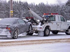 Tow truck hauling a wrecked car away in winter.