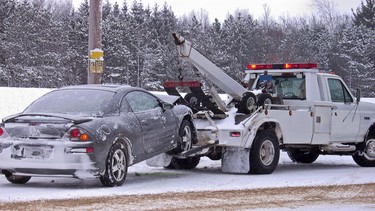 Tow truck hauling a wrecked car away in winter.