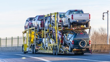 Big rig yellow car hauler semi truck transporting cars on two levels semi trailer driving on the overpass road