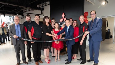 Tammy Roach, cutting the ribbon with Juyu Jeon, president and CEO, Mitsubishi Motor Sales of Canada, to celebrate the grand opening of Charlottetown Mitsubishi, surrounded by staff and family.