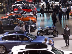 People walk through the BMW showroom Wednesday, March 28, 2018, at the New York Auto Show.