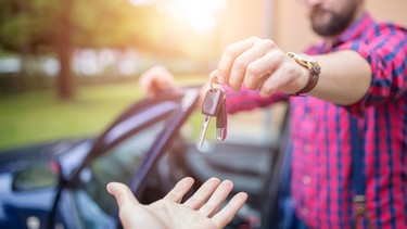 Man standing by the car and giving back car keys