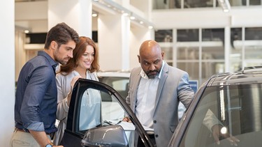 Salesman showing car features to couple