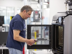 Dave Jacek, 3D printing technician, unloads 3D printed medical face shield parts at Ford’s Advanced Manufacturing Center.
