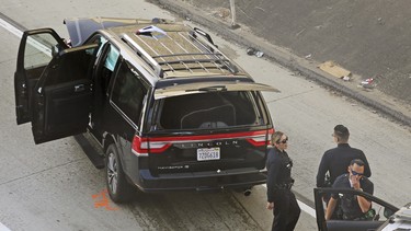 Los Angeles police officers stand after a pursuit of a stolen hearse with with a casket and body inside on Interstate 110 in South Los Angeles Thursday, Feb. 27, 2020.