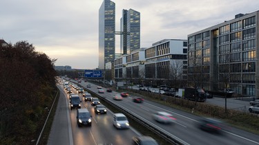 Busy road with modern office building in Munich, Germany, during the golden hour