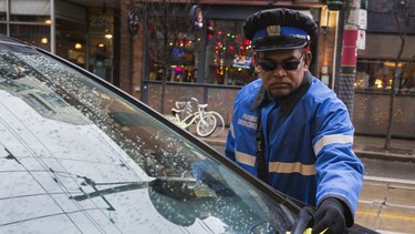 A parking enforcement officer places a ticket on a car on King St E in Toronto, Ont. on Monday December 21, 2015. Ernest Doroszuk/Toronto Sun/Postmedia Network